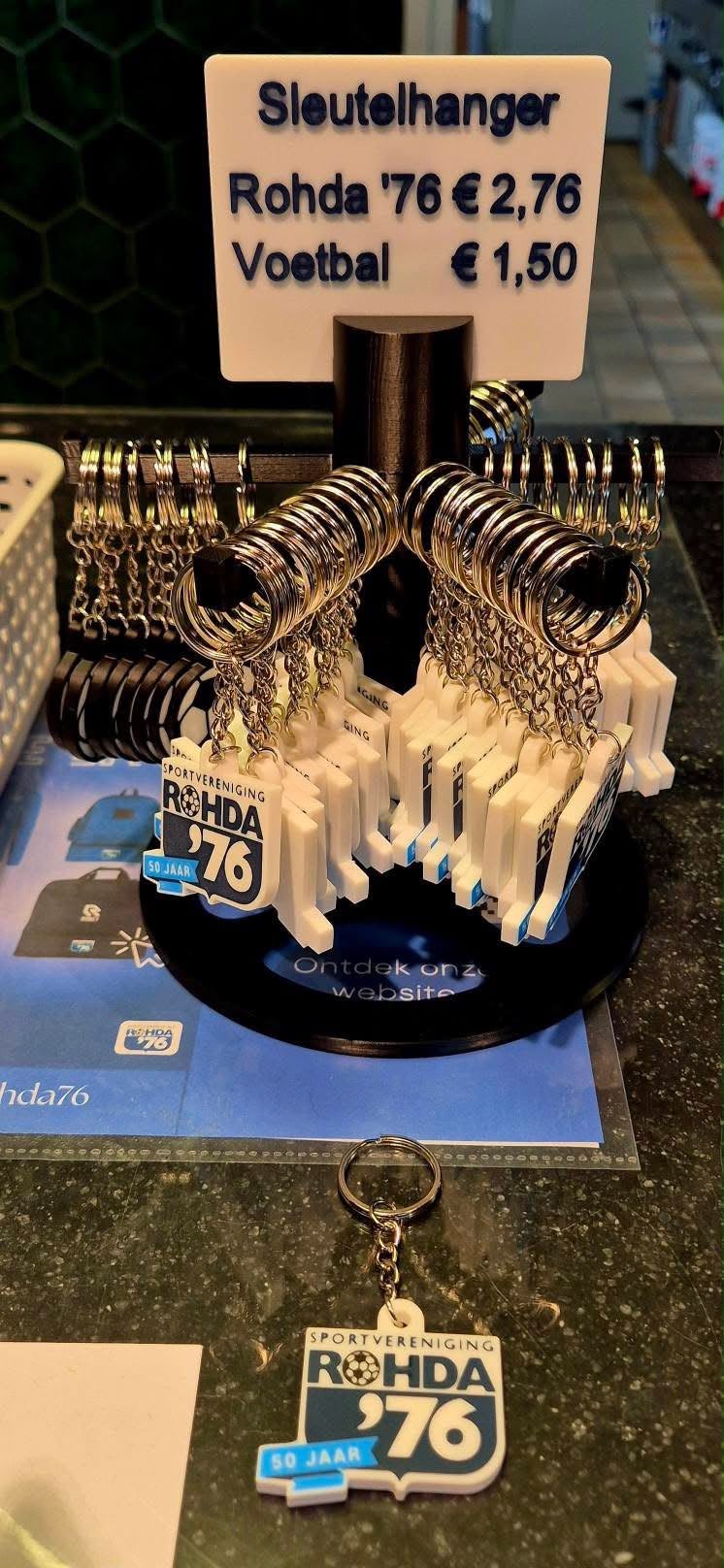Sleutelhangerstandaard met Rohda '76 jubileum-sleutelhangers bij de kassa